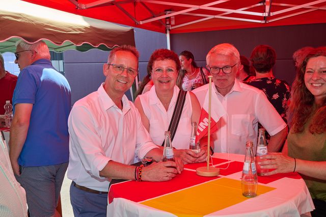 Glückliche Gruppe von vier Personen bei einem Fest mit Getränken und Tischdekoration.