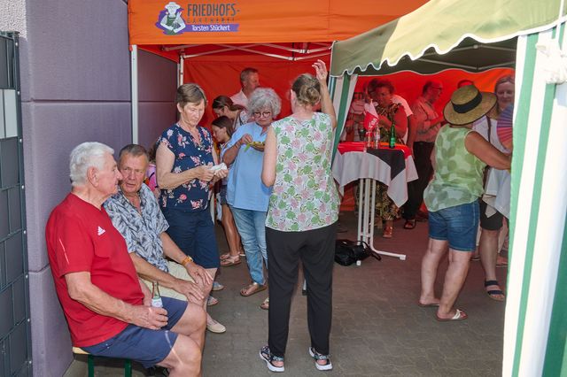 Gruppe von Menschen unter Pavillon bei geselligem Beisammensein und Gesprächen.